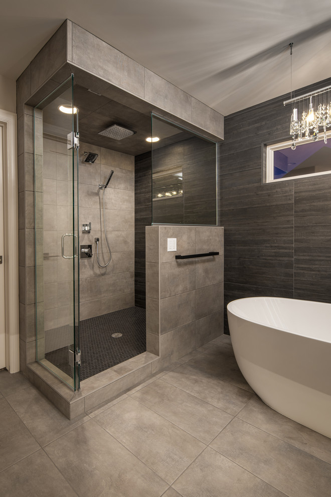 Пример оригинального дизайна: большая главная ванная комната в стиле модернизм с плоскими фасадами, темными деревянными фасадами, отдельно стоящей ванной, угловым душем, раздельным унитазом, серой плиткой, керамогранитной плиткой, серыми стенами, полом из керамогранита, врезной раковиной, столешницей из кварцита, серым полом, душем с распашными дверями и белой столешницей