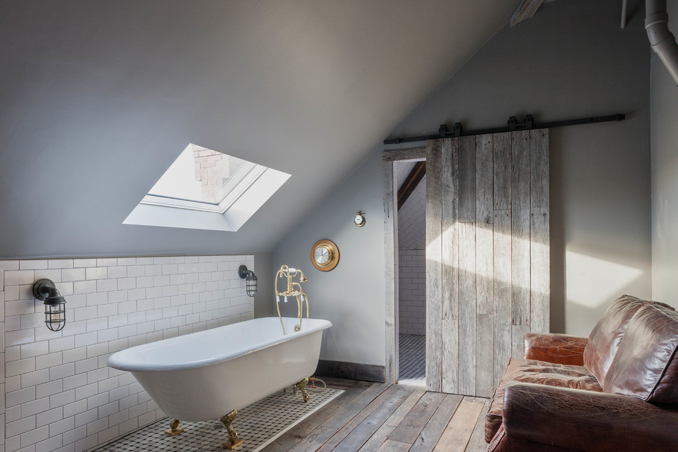 На фото: ванная комната в стиле рустика с ванной на ножках, серыми стенами и темным паркетным полом с
