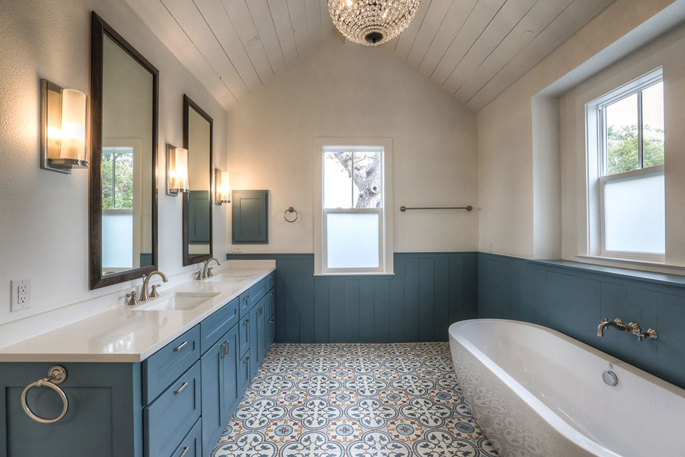 Идея дизайна: главная ванная комната среднего размера в стиле кантри с фасадами в стиле шейкер, синими фасадами, отдельно стоящей ванной, разноцветной плиткой, керамической плиткой, белыми стенами, полом из керамической плитки, врезной раковиной и мраморной столешницей