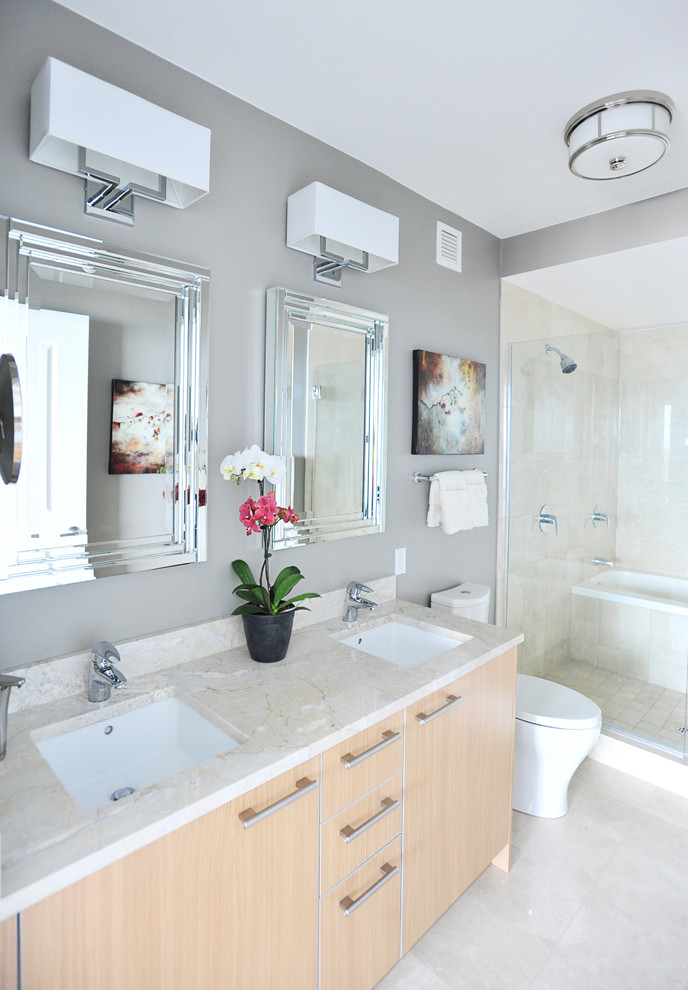 Mid-sized trendy master beige tile white floor bathroom photo in Chicago with flat-panel cabinets, light wood cabinets, a one-piece toilet, gray walls, an undermount sink, granite countertops, a hinged shower door and beige countertops