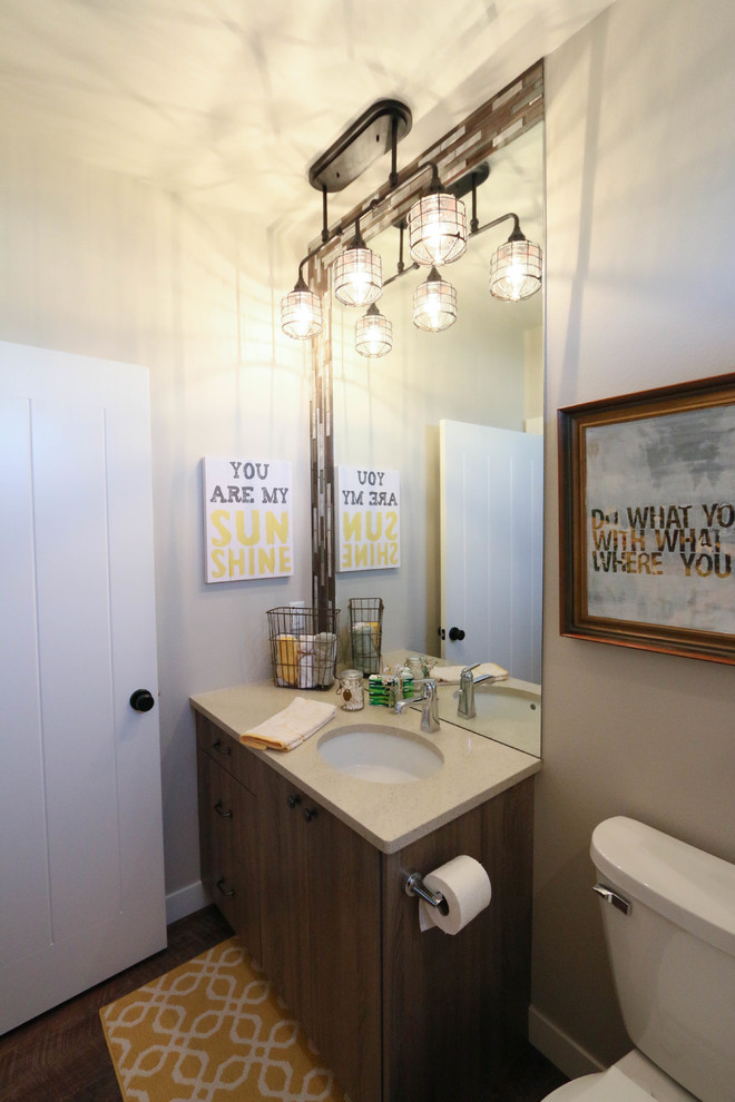 Cette photo montre une salle de bain industrielle en bois vieilli de taille moyenne avec un placard à porte plane, un plan de toilette en quartz, une baignoire en alcôve, WC séparés, un carrelage beige, mosaïque, un mur gris, un sol en vinyl et un lavabo encastré.