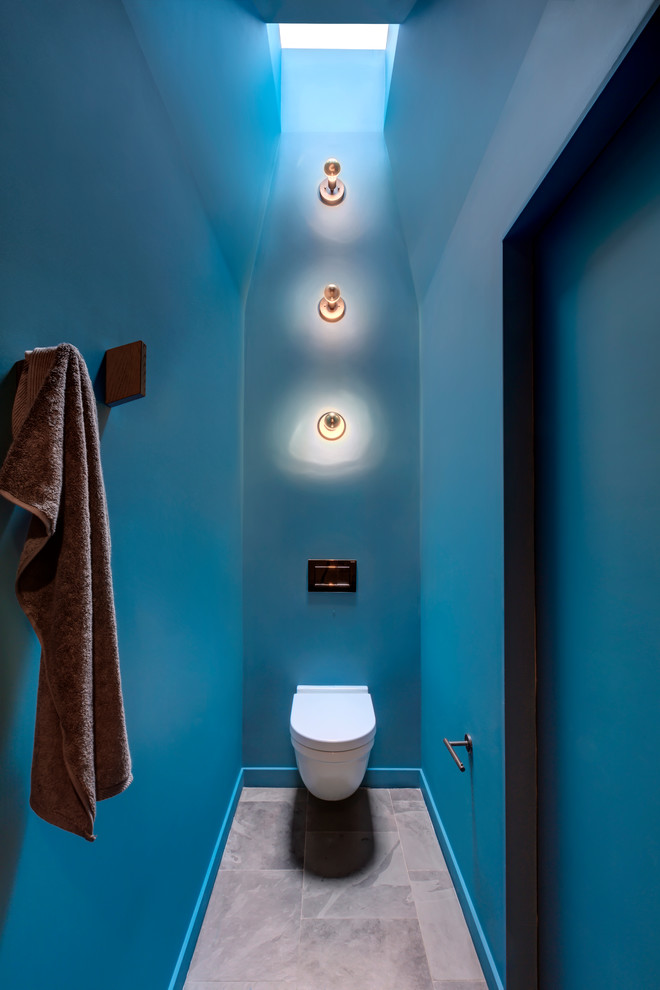 Пример оригинального дизайна: туалет в стиле модернизм с плоскими фасадами, светлыми деревянными фасадами, черной плиткой, синими стенами, полом из сланца, врезной раковиной, столешницей из искусственного кварца, серым полом и белой столешницей