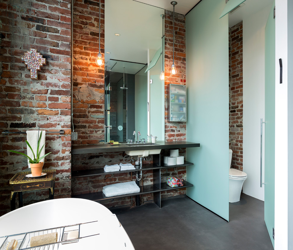Urban concrete floor freestanding bathtub photo in Seattle with an undermount sink, open cabinets and a one-piece toilet