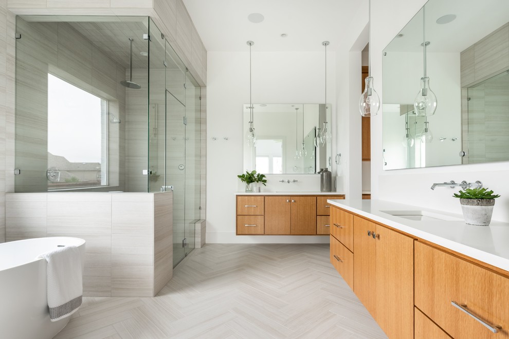 Contemporary bathroom in Dallas with flat-panel cabinets, medium wood cabinets, a freestanding bath, a corner shower, beige tiles, white walls, a submerged sink, beige floors, a hinged door and white worktops.