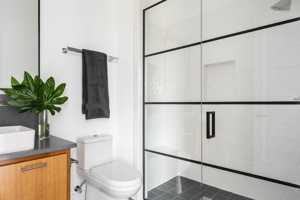 Réalisation d'une salle de bain avec un mur blanc, une cabine de douche à porte battante et un plan de toilette gris.