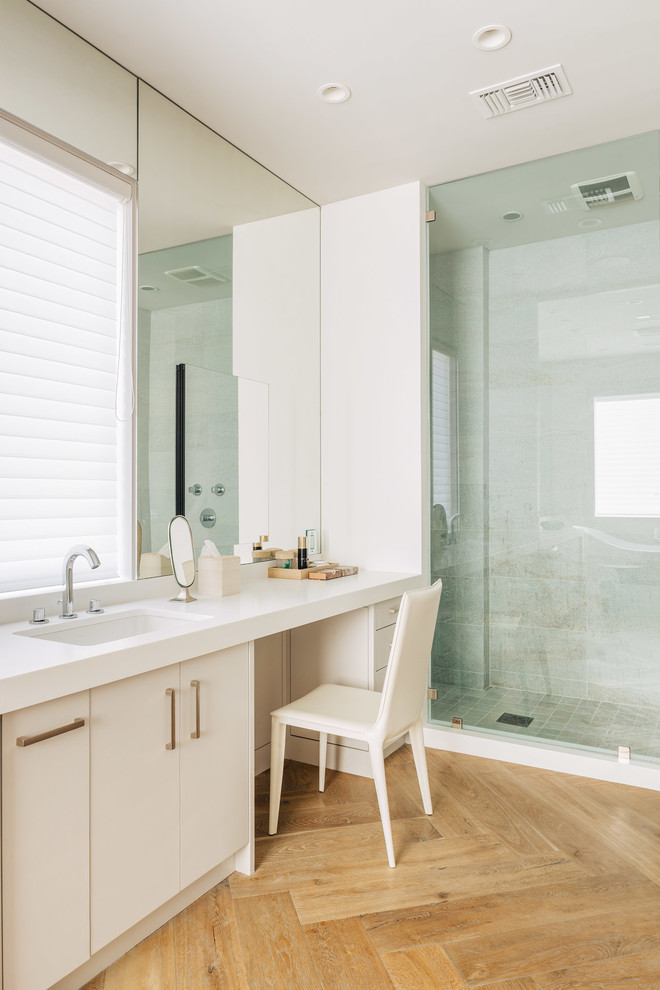 Diseño de cuarto de baño contemporáneo con lavabo bajoencimera, armarios con paneles lisos, puertas de armario blancas, ducha empotrada, baldosas y/o azulejos blancos, paredes blancas y suelo de madera en tonos medios