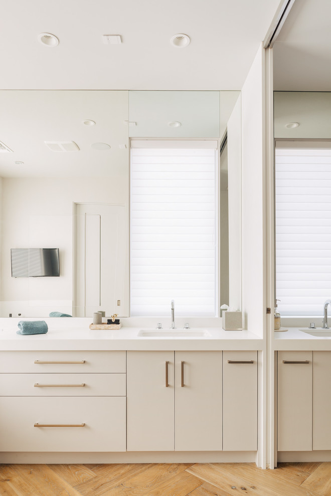 Ejemplo de cuarto de baño principal actual con puertas de armario blancas, bañera exenta, encimera de acrílico y encimeras blancas