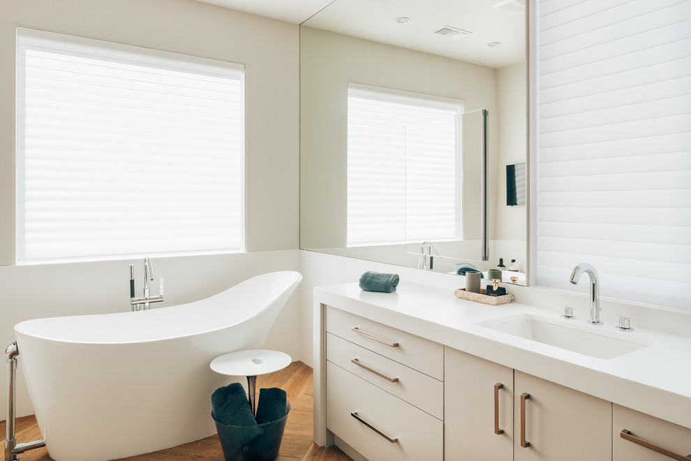 Foto de cuarto de baño principal actual con puertas de armario blancas, bañera exenta, encimera de acrílico y encimeras blancas