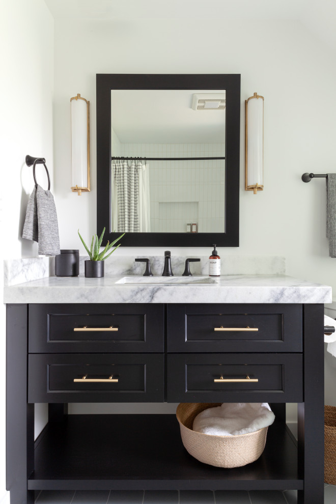 This is an example of a medium sized classic bathroom in Chicago with shaker cabinets, black cabinets, an alcove bath, a shower/bath combination, a two-piece toilet, white tiles, metro tiles, white walls, a submerged sink, marble worktops, grey floors, a shower curtain and white worktops.
