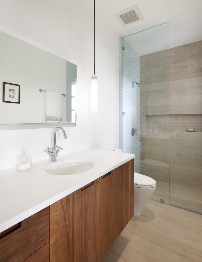 サンフランシスコにあるコンテンポラリースタイルのおしゃれな浴室 (アンダーカウンター洗面器、フラットパネル扉のキャビネット、中間色木目調キャビネット、アルコーブ型シャワー、ベージュのタイル、白い洗面カウンター) の写真
