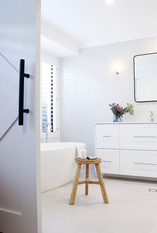 Стильный дизайн: главная ванная комната среднего размера в современном стиле с фасадами с утопленной филенкой, белыми фасадами, отдельно стоящей ванной, унитазом-моноблоком, белой плиткой, плиткой кабанчик, белыми стенами, полом из керамической плитки, врезной раковиной, столешницей из искусственного кварца и белой столешницей - последний тренд