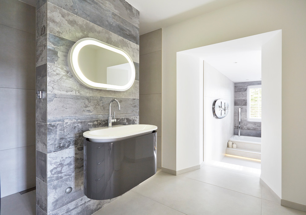 Bild på ett stort funkis en-suite badrum, med grå skåp, ett platsbyggt badkar, en öppen dusch, en vägghängd toalettstol, grå kakel, porslinskakel, beige väggar, ett väggmonterat handfat och klinkergolv i porslin