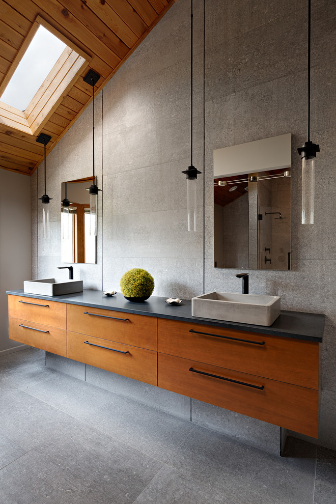 Idées déco pour une grande salle de bain principale contemporaine en bois brun avec un placard à porte plane, un carrelage gris, un mur gris, une vasque, un sol gris, un plan de toilette noir, sol en béton ciré et un plan de toilette en béton.