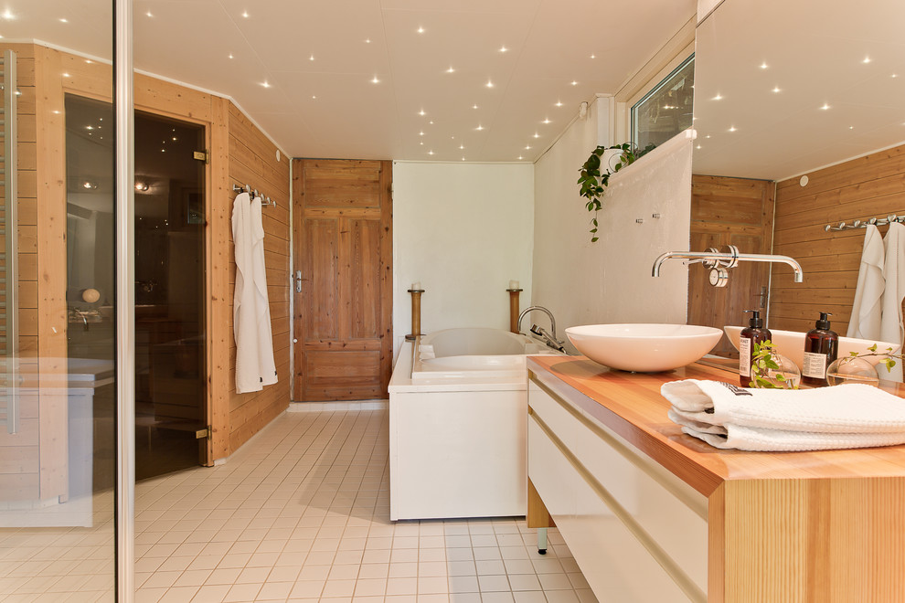 Minimalistisk inredning av ett stort beige beige en-suite badrum, med släta luckor, vita skåp, ett platsbyggt badkar, våtrum, vita väggar, klinkergolv i keramik, ett fristående handfat, träbänkskiva, vitt golv och dusch med gångjärnsdörr