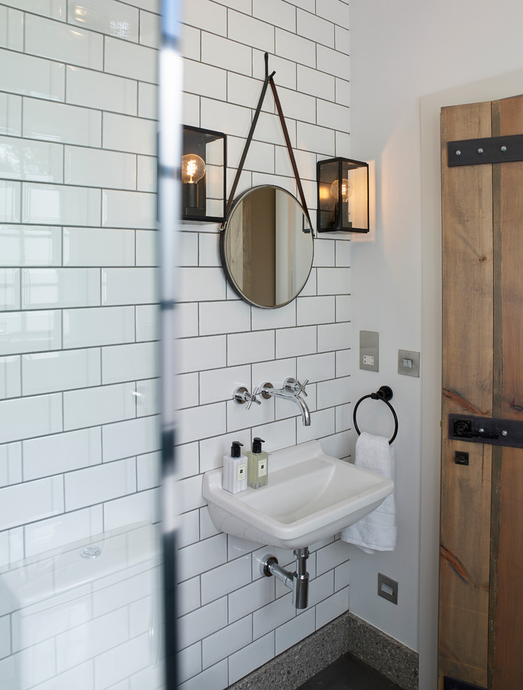 Foto på ett industriellt badrum med dusch, med en öppen dusch, en toalettstol med separat cisternkåpa, grå väggar, betonggolv och ett väggmonterat handfat