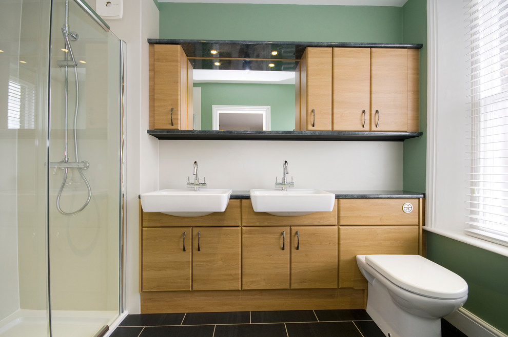 На фото: ванная комната в стиле модернизм с монолитной раковиной, плоскими фасадами, фасадами цвета дерева среднего тона, столешницей из ламината, душем в нише, унитазом-моноблоком, зелеными стенами и полом из линолеума с