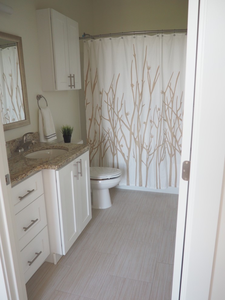 Idéer för ett mellanstort klassiskt en-suite badrum, med luckor med infälld panel, vita skåp, en dusch/badkar-kombination, en toalettstol med separat cisternkåpa, beige kakel, stenkakel, vita väggar, klinkergolv i porslin, ett undermonterad handfat och granitbänkskiva