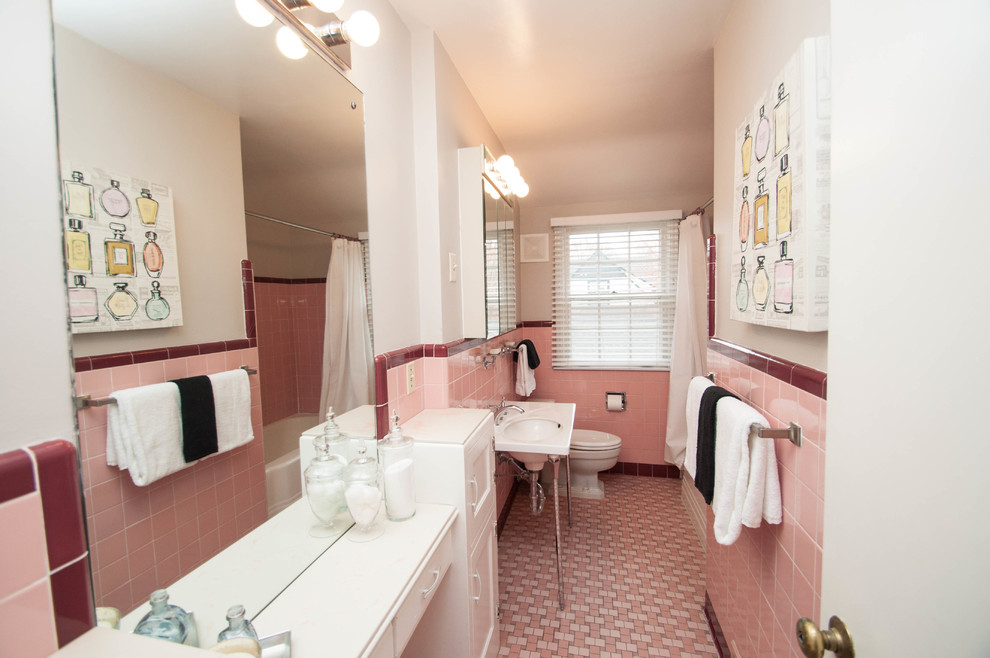 ミネアポリスにある低価格の中くらいなトラディショナルスタイルのおしゃれな子供用バスルーム (落し込みパネル扉のキャビネット、白いキャビネット、ドロップイン型浴槽、シャワー付き浴槽	、一体型トイレ	、ピンクのタイル、セラミックタイル、白い壁、セラミックタイルの床、ペデスタルシンク、木製洗面台、ピンクの床、シャワーカーテン、白い洗面カウンター) の写真