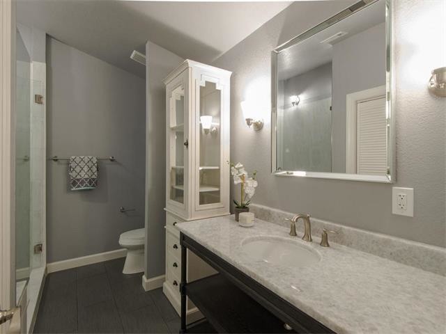 Exemple d'une salle de bain principale tendance avec un placard sans porte, des portes de placard noires, un carrelage gris, un mur gris, un sol en carrelage de céramique et un plan de toilette en quartz modifié.