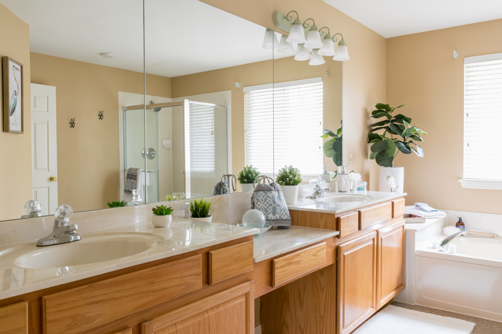 Inspiration for a large transitional master brown floor bathroom remodel in St Louis with raised-panel cabinets, medium tone wood cabinets, beige walls, an integrated sink, solid surface countertops, a hinged shower door and beige countertops
