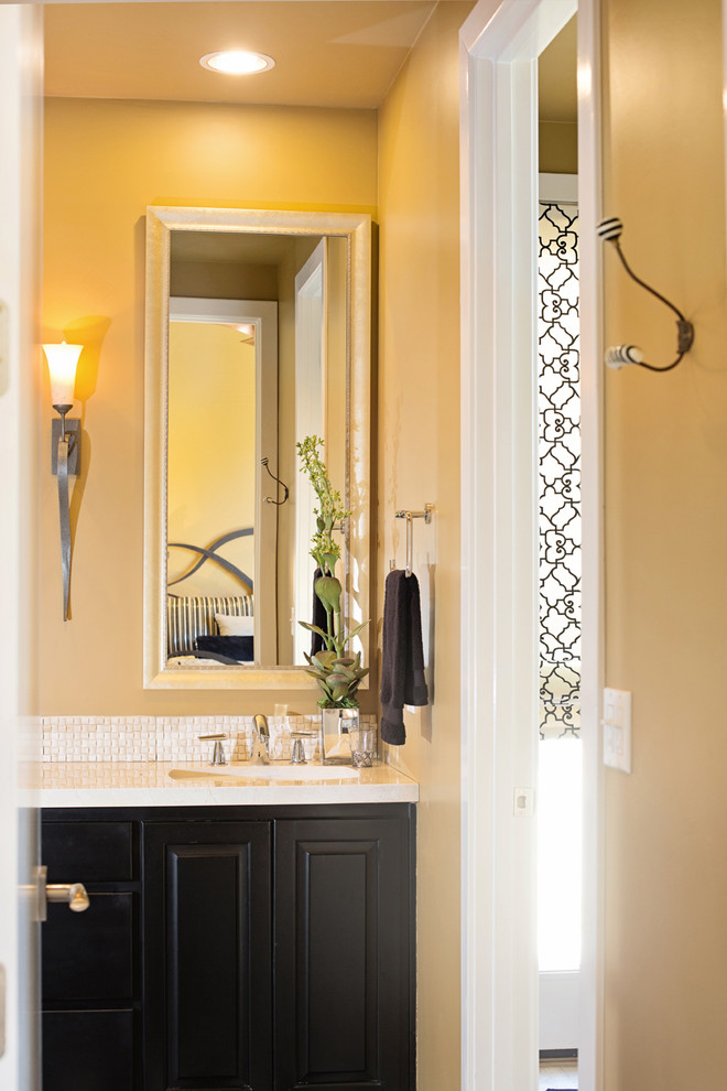 Inspiration pour une salle de bain traditionnelle en bois foncé avec un lavabo encastré, un placard avec porte à panneau encastré, un plan de toilette en quartz modifié, un carrelage beige et un mur jaune.