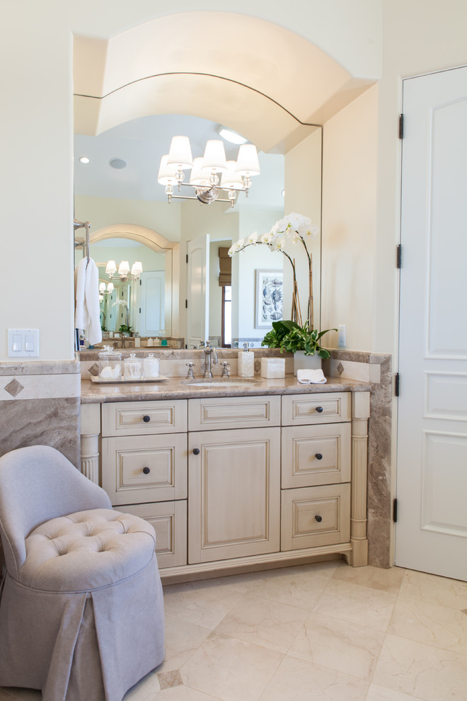 Foto di una grande stanza da bagno padronale mediterranea con lavabo sottopiano, consolle stile comò, ante con finitura invecchiata, top in marmo, vasca ad alcova, piastrelle beige, piastrelle in pietra e pavimento in marmo