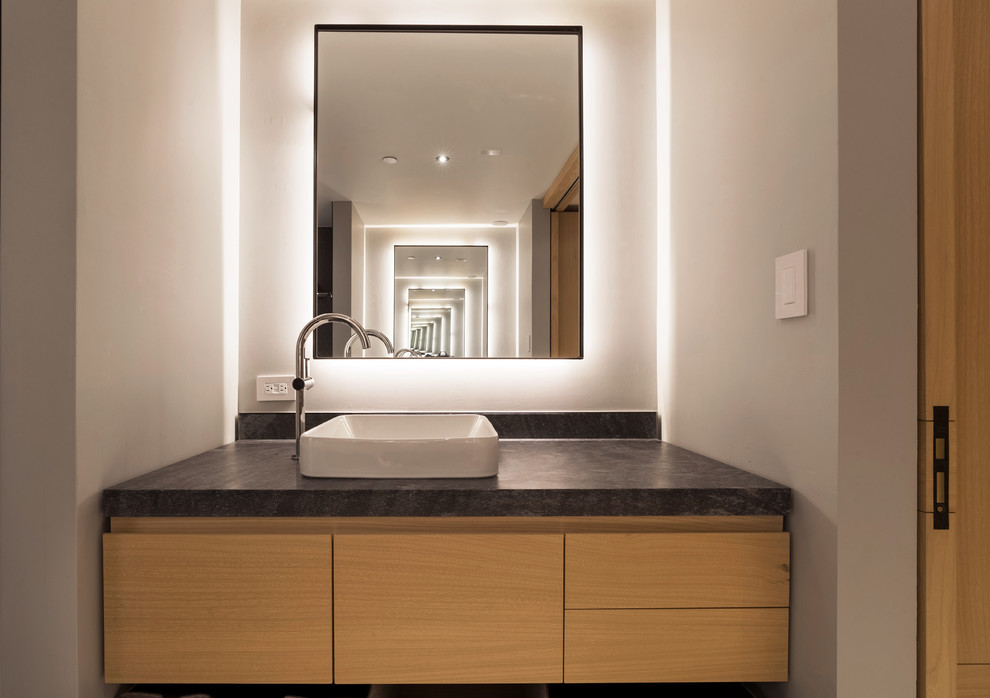 Exemple d'un WC et toilettes moderne en bois clair de taille moyenne avec un placard à porte plane, une vasque, un plan de toilette en granite, un plan de toilette gris, un mur blanc et meuble-lavabo suspendu.