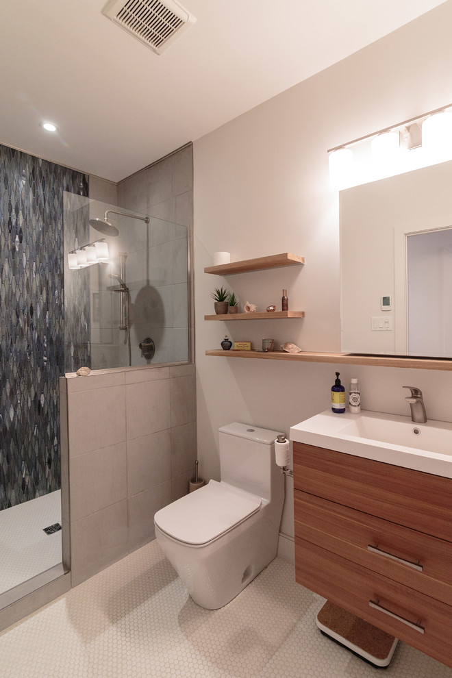 Modern inredning av ett mellanstort badrum med dusch, med släta luckor, skåp i mellenmörkt trä, en toalettstol med hel cisternkåpa, vita väggar, ett integrerad handfat, vitt golv, med dusch som är öppen, en dusch i en alkov, blå kakel, flerfärgad kakel, vit kakel, mosaik och vinylgolv