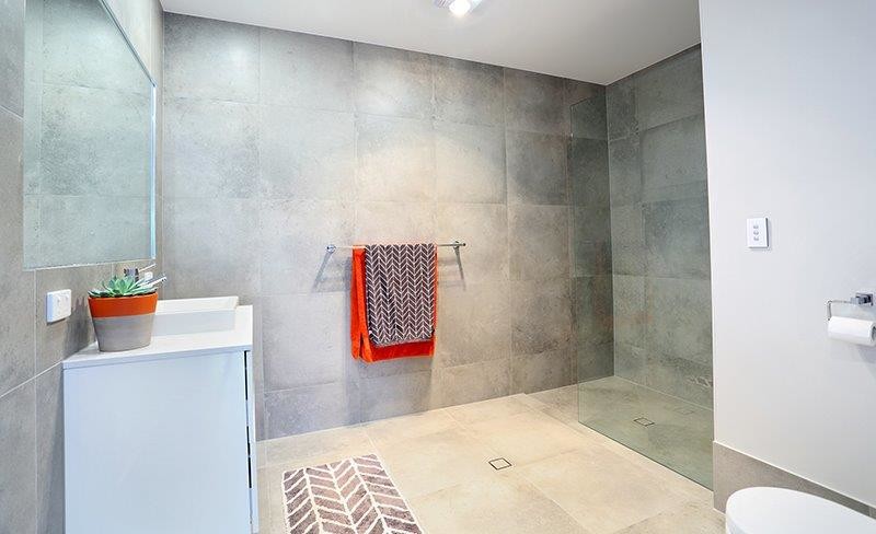 Cette photo montre une grande salle de bain moderne avec des portes de placard blanches, une douche ouverte, WC suspendus, un carrelage gris, des carreaux de porcelaine, un mur gris, un sol en carrelage de porcelaine, un lavabo posé et un plan de toilette en quartz modifié.