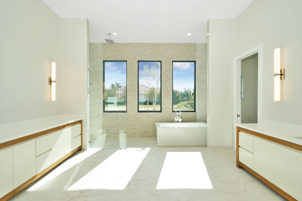 Свежая идея для дизайна: большая главная ванная комната в стиле модернизм с плоскими фасадами, белыми фасадами, отдельно стоящей ванной, душевой комнатой, бежевой плиткой, плиткой мозаикой, бежевыми стенами, мраморным полом, врезной раковиной, столешницей из искусственного камня, белым полом и открытым душем - отличное фото интерьера