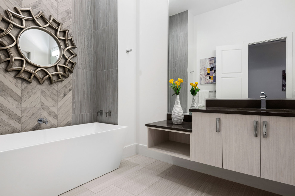 Bild på ett stort funkis brun brunt en-suite badrum, med släta luckor, beige skåp, ett fristående badkar, grå kakel, porslinskakel, vita väggar, klinkergolv i porslin och beiget golv