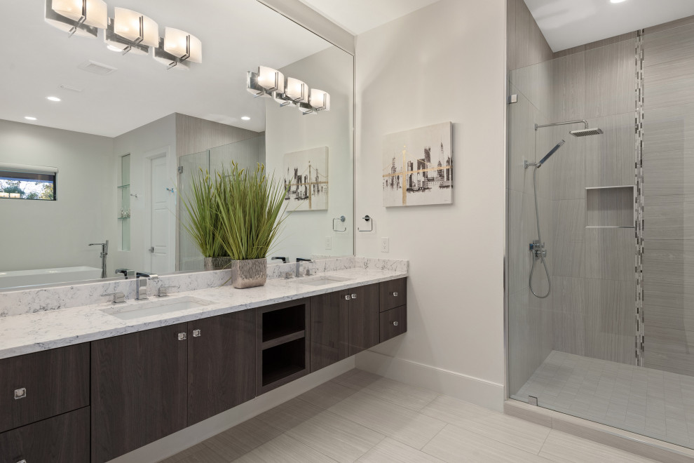 This is an example of a large contemporary ensuite bathroom in Orlando with flat-panel cabinets, brown cabinets, a freestanding bath, an alcove shower, grey tiles, porcelain tiles, grey walls, porcelain flooring, a submerged sink, grey floors, a hinged door and grey worktops.