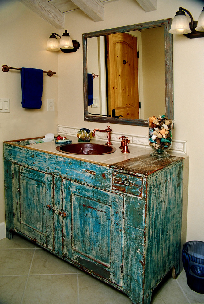 Réalisation d'une salle de bain style shabby chic avec un lavabo posé et des portes de placard bleues.