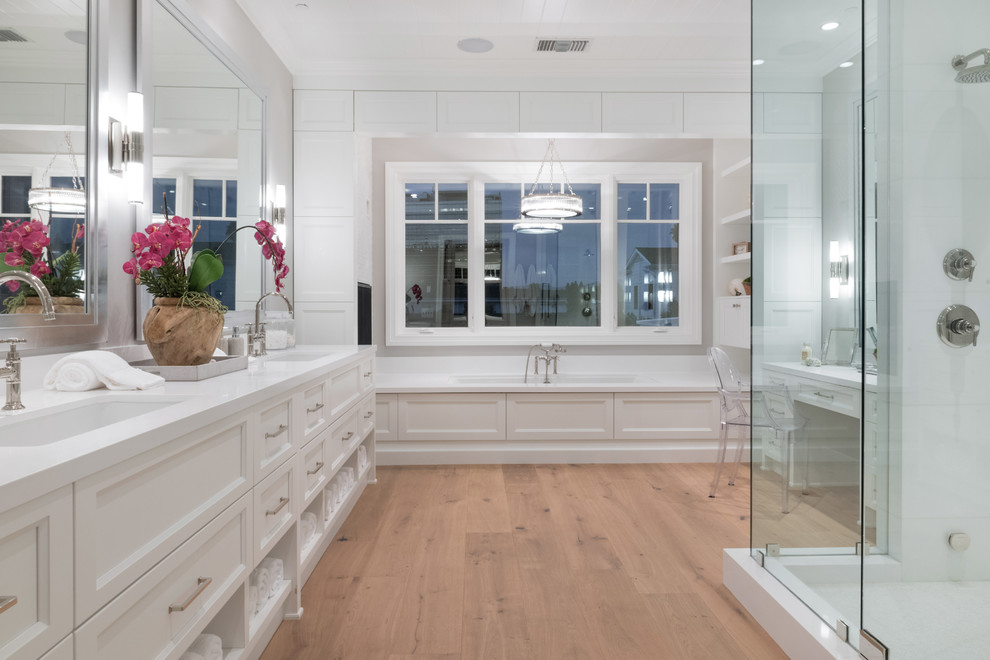 Design ideas for an expansive classic ensuite bathroom in Los Angeles with recessed-panel cabinets, white cabinets, a hot tub, a double shower, grey walls, light hardwood flooring, a submerged sink and engineered stone worktops.