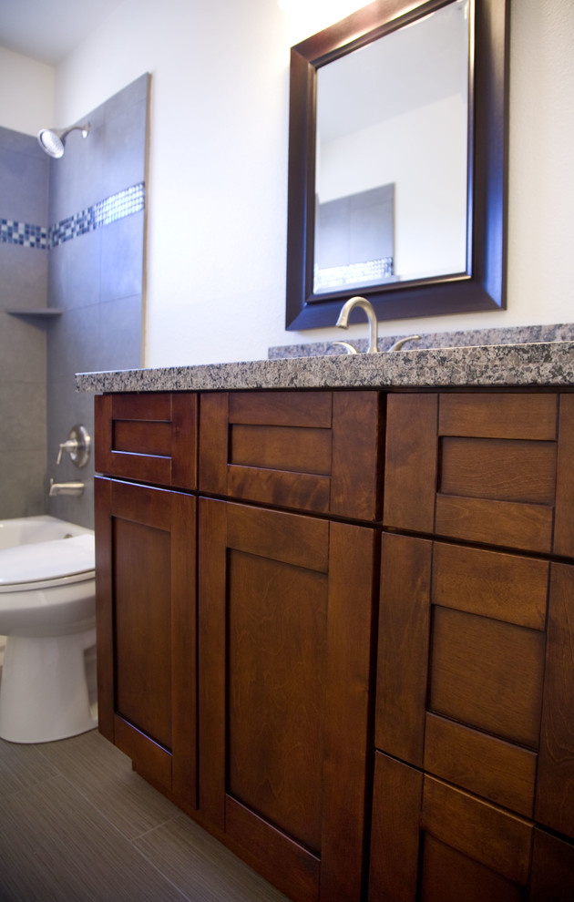 Diseño de cuarto de baño clásico renovado con armarios estilo shaker, puertas de armario de madera oscura, ducha esquinera y encimera de granito