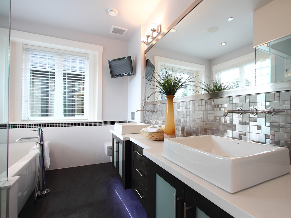 Immagine di una stanza da bagno contemporanea con vasca freestanding, lavabo a bacinella e pavimento nero