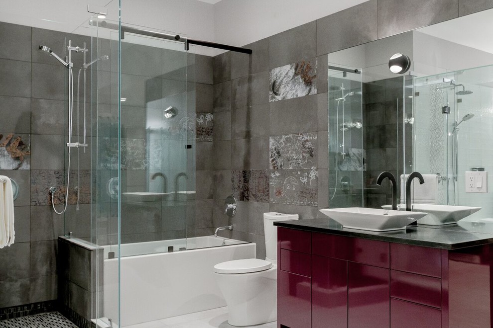 Modern inredning av ett stort en-suite badrum, med ett fristående handfat, grå väggar, släta luckor, röda skåp, ett badkar i en alkov, en dusch/badkar-kombination, en toalettstol med hel cisternkåpa, grå kakel, klinkergolv i keramik, granitbänkskiva och cementkakel