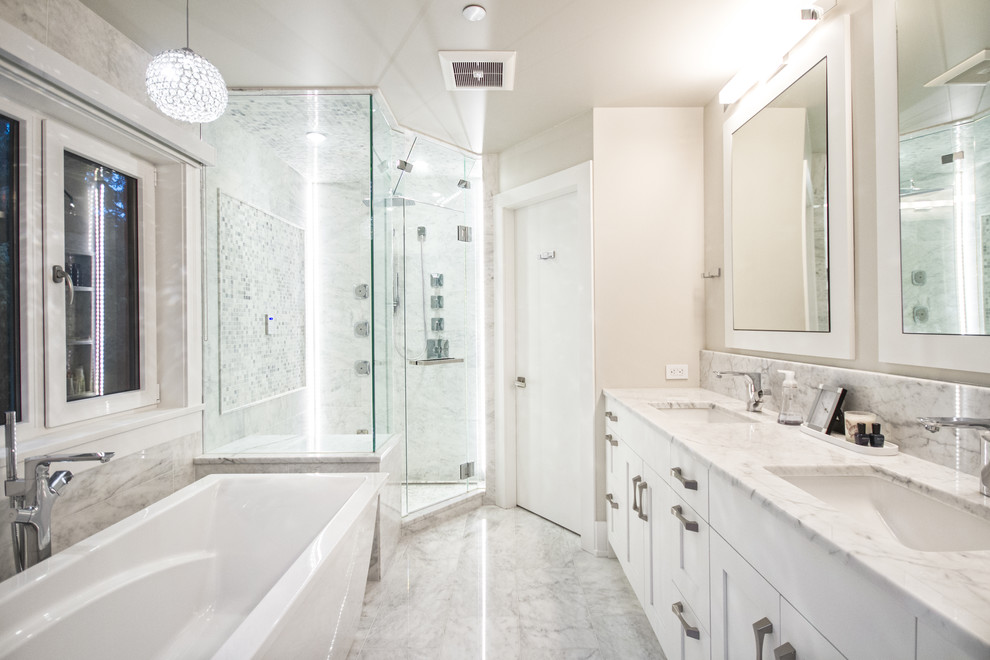 Foto på ett funkis en-suite badrum, med skåp i shakerstil, vita skåp, ett fristående badkar, en hörndusch, vit kakel, stenkakel, grå väggar, marmorgolv, marmorbänkskiva och ett undermonterad handfat