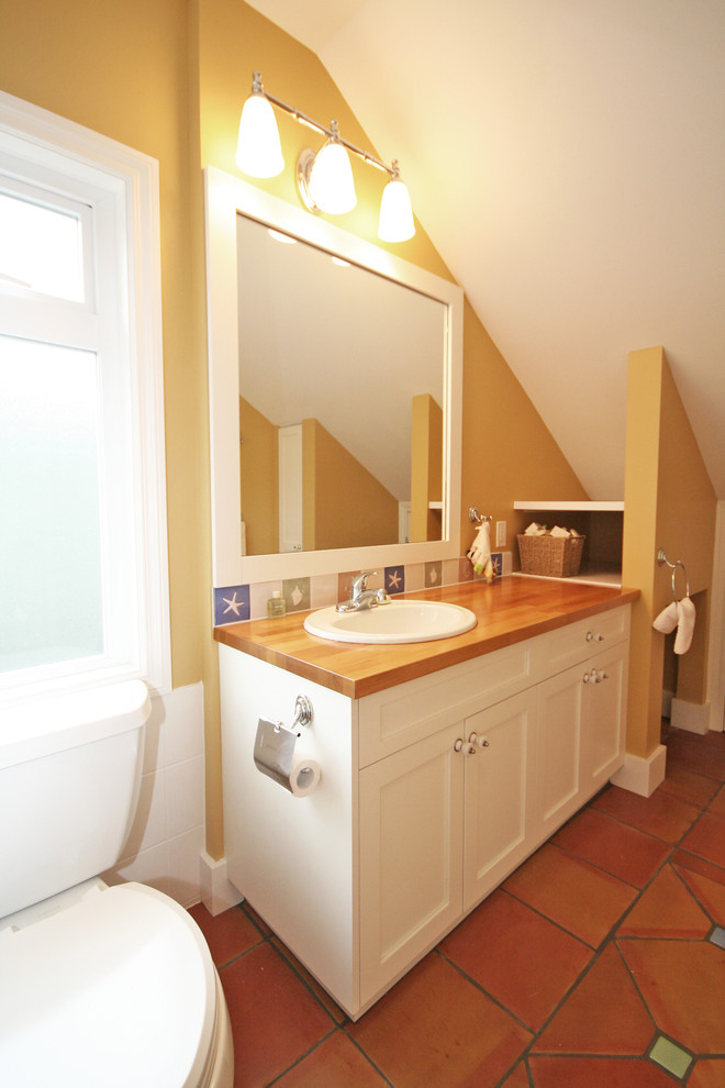 Inspiration for a medium sized classic family bathroom in Vancouver with a built-in sink, shaker cabinets, white cabinets, wooden worktops, a two-piece toilet, white tiles, beige walls and terracotta flooring.