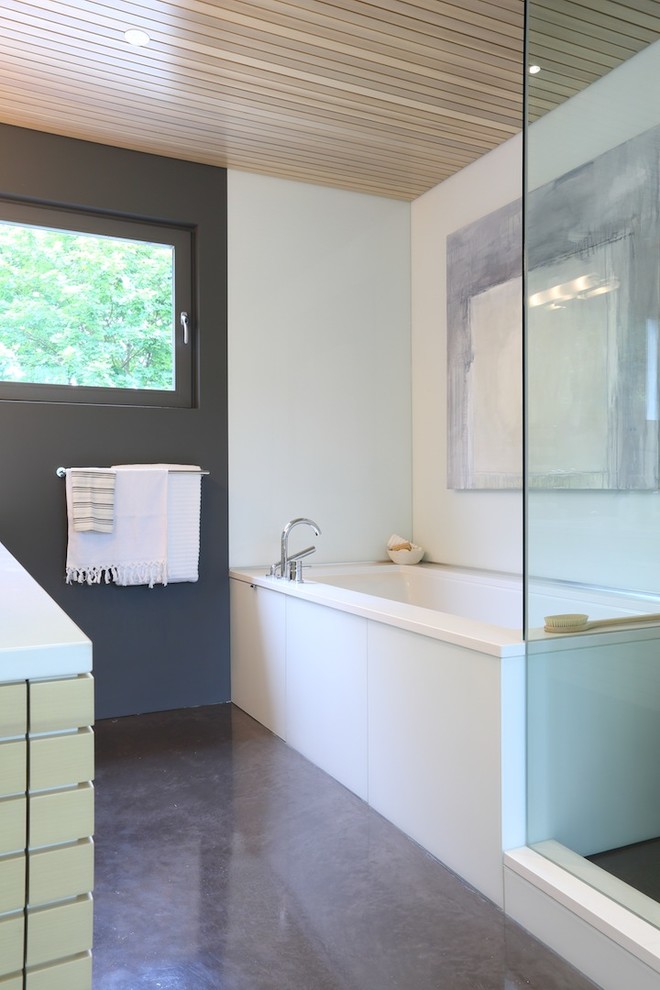 Aménagement d'une grande salle de bain principale contemporaine en bois clair avec un lavabo encastré, une baignoire encastrée, WC à poser, un mur blanc et sol en béton ciré.