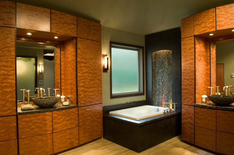 Cette photo montre une grande salle de bain principale tendance en bois brun avec un placard en trompe-l'oeil, une vasque, un plan de toilette en granite, une baignoire d'angle, un mur beige et parquet clair.