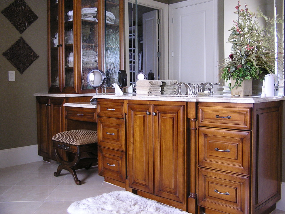 Ispirazione per una stanza da bagno classica con lavabo sottopiano, ante con bugna sagomata e ante in legno scuro