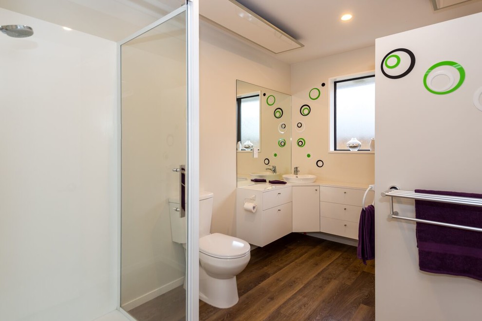 Imagen de cuarto de baño contemporáneo con lavabo sobreencimera, armarios con paneles lisos, puertas de armario blancas, encimera de laminado, paredes beige y suelo vinílico