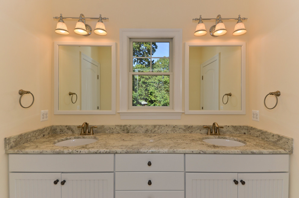 Diseño de cuarto de baño principal actual de tamaño medio con lavabo bajoencimera, paredes blancas, armarios con paneles lisos, puertas de armario blancas y encimera de granito