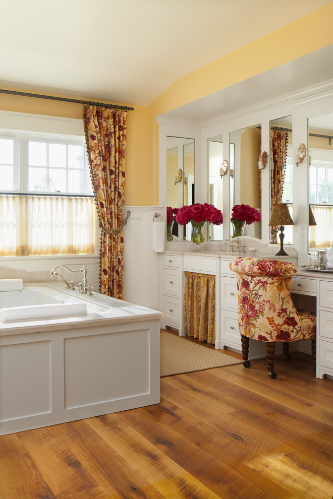 Foto di una stanza da bagno country con ante in stile shaker, ante bianche, vasca da incasso, pareti gialle e pavimento in legno massello medio