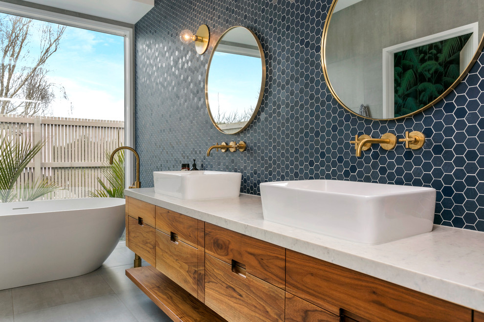 Свежая идея для дизайна: главная ванная комната в современном стиле с отдельно стоящей ванной, настольной раковиной, коричневыми фасадами, душем без бортиков, инсталляцией, синей плиткой, плиткой мозаикой, синими стенами, полом из сланца, мраморной столешницей, коричневым полом, открытым душем и плоскими фасадами - отличное фото интерьера