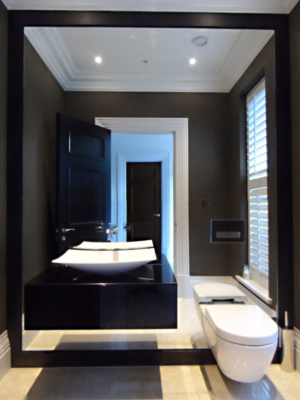 Foto på ett funkis svart en-suite badrum, med släta luckor, svarta skåp, en vägghängd toalettstol, bruna väggar, marmorgolv, ett piedestal handfat, bänkskiva i glas och beiget golv