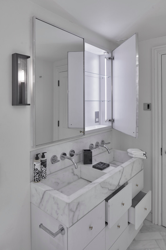 Cette image montre une salle de bain minimaliste de taille moyenne pour enfant avec un placard à porte vitrée, des portes de placard blanches, une baignoire posée, un combiné douche/baignoire, un carrelage blanc, un sol en marbre, un lavabo suspendu, un plan de toilette en marbre, un sol blanc et une cabine de douche à porte battante.