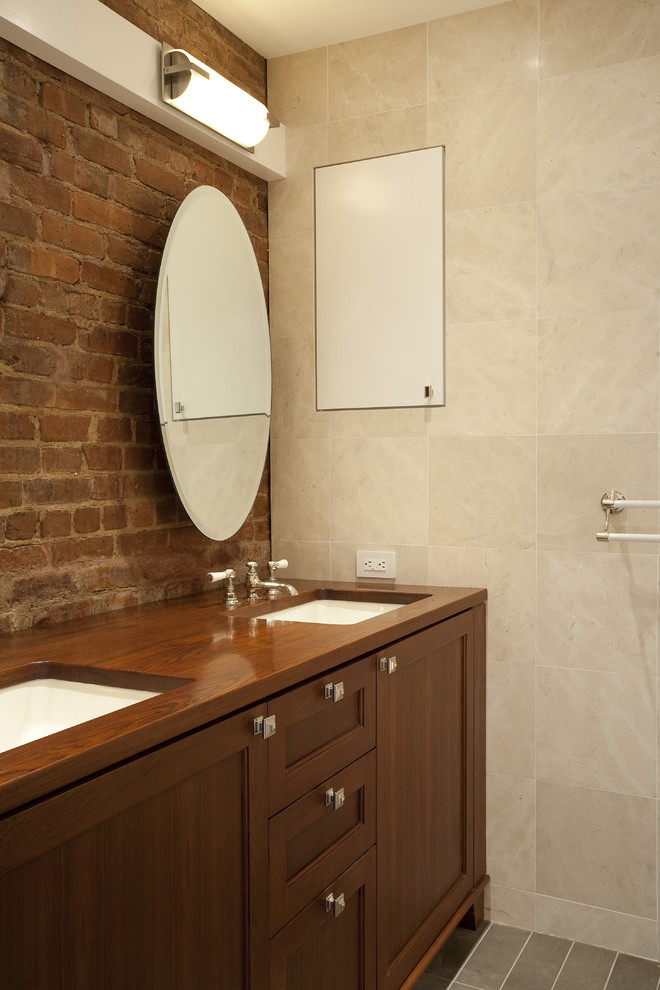 Modelo de cuarto de baño bohemio con lavabo bajoencimera, armarios estilo shaker, puertas de armario de madera oscura y baldosas y/o azulejos beige