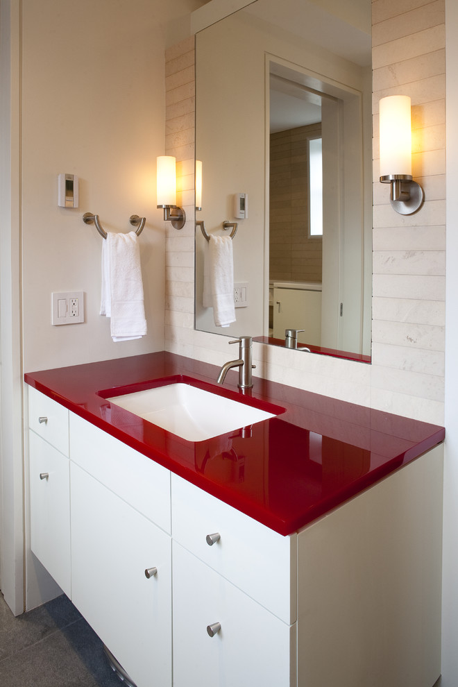 На фото: ванная комната среднего размера в современном стиле с врезной раковиной, плоскими фасадами, белыми фасадами, белой плиткой, каменной плиткой, белыми стенами и стеклянной столешницей